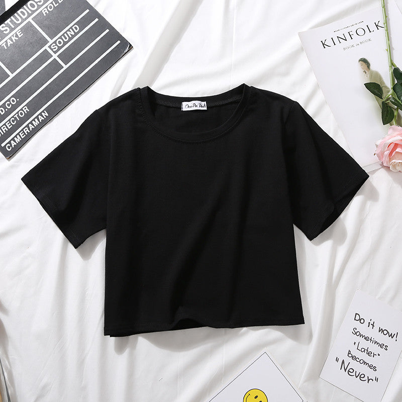 Black cropped t-shirt laid flat on a white bed background, minimalist femboy clothing essential designed for pairing with skirts and thigh highs.