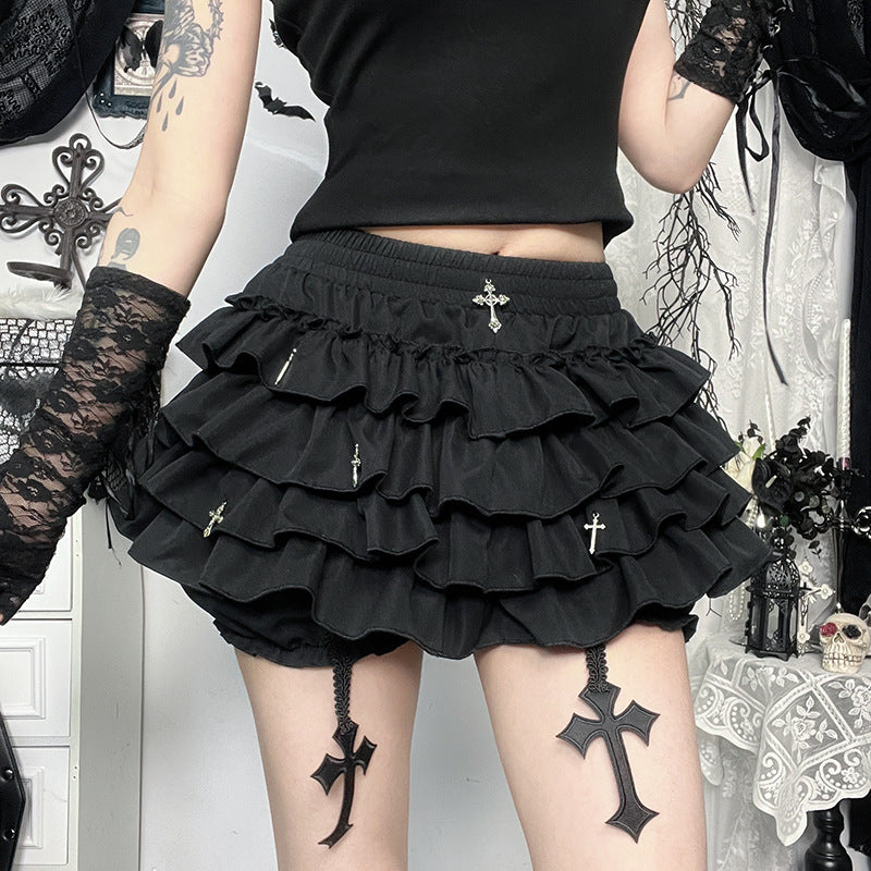 Waist-down shot of black gothic femboy skirt with tiered ruffles and silver cross pendants, styled with lace armwear – femboy skirt outfit aesthetic