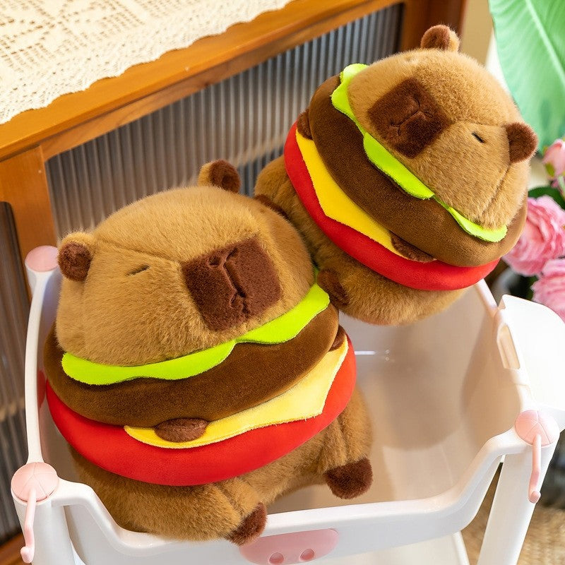 Capybara Burger Plush placed inside a small storage basket, showing the soft plush texture, rounded capybara face, and colorful burger layers in a warm indoor environment.
