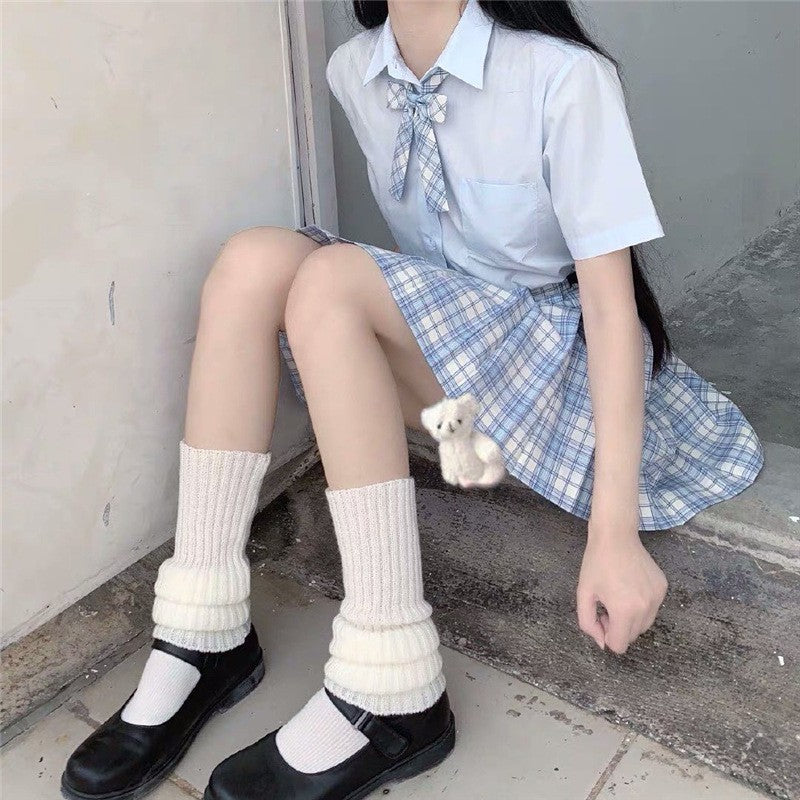 Cream knitted leg warmers worn with loafers and pastel plaid skirt, cute cozy femboy clothing style