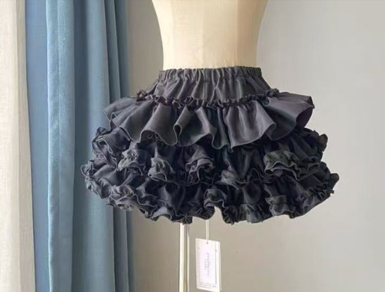 Charcoal grey tiered femboy skirt displayed on mannequin, featuring deep layered ruffles and elastic waistband, studio side view highlighting punk-inspired femboy fashion and gothic femboy outfit styling.