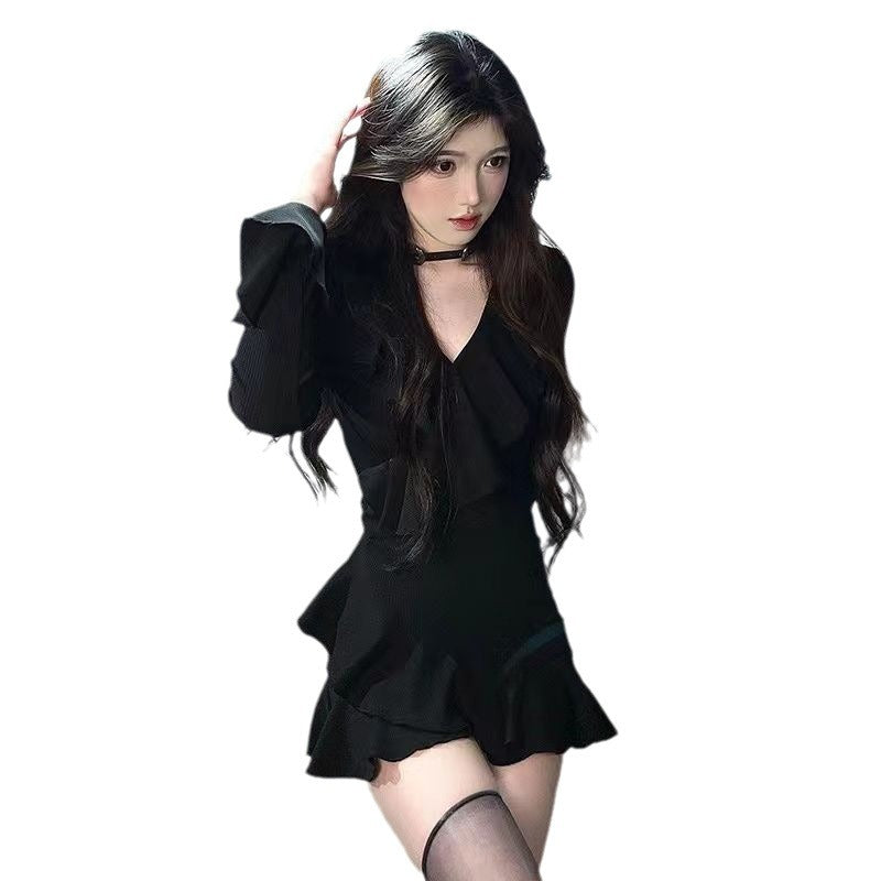 Front view of a model wearing a black ruffle sleeve dress with a v-neckline and fitted waist, styled as a femboy outfit. The dress features a flared hem, exuding elegance with a hint of goth-inspired fashion, perfect for autumn and winter seasons.