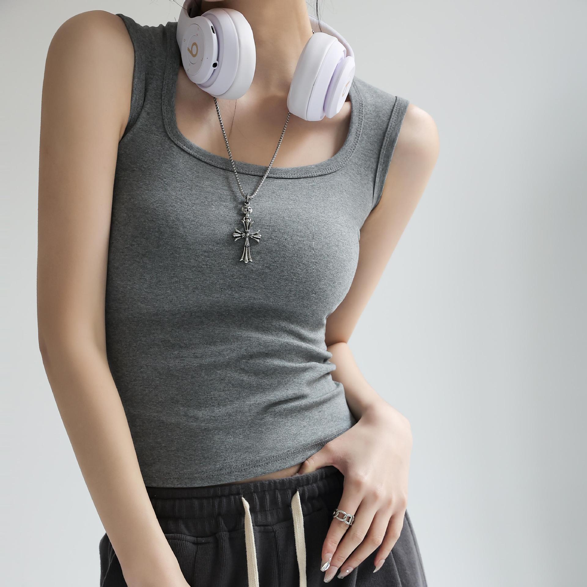 Grey femboy cotton tank top with a slim fitted cut, sleeveless scoop neckline, worn by an androgynous model accessorised with a silver necklace and headphones, clean studio background.