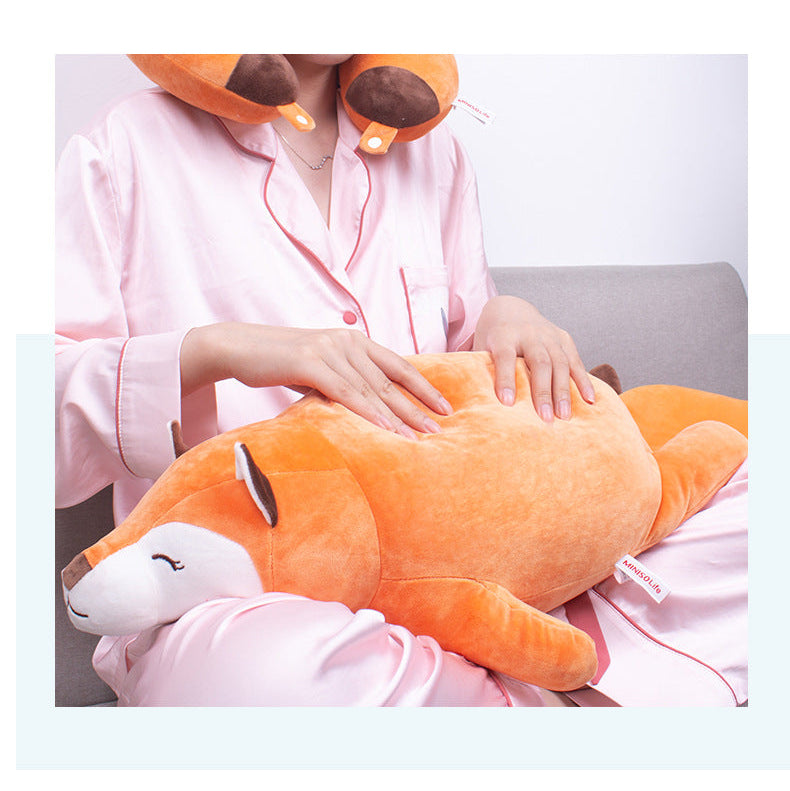 Close lifestyle shot of a model holding the Femboy Fox Plushie while wearing pink satin pajamas, photographed from a front-facing mid-range angle with warm indoor lighting, featuring a soft orange and white color palette, styled as a cozy bedroom accessory from a femboy clothing store.