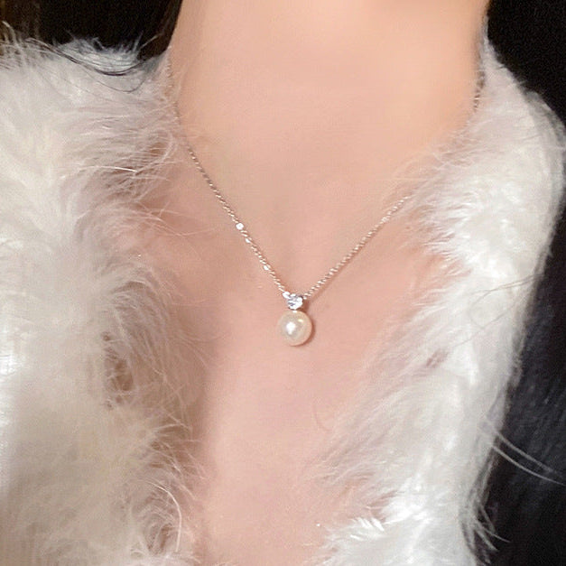 Model wearing a pearl pendant necklace paired with a soft fur coat, showcasing elegant femboy fashion style.