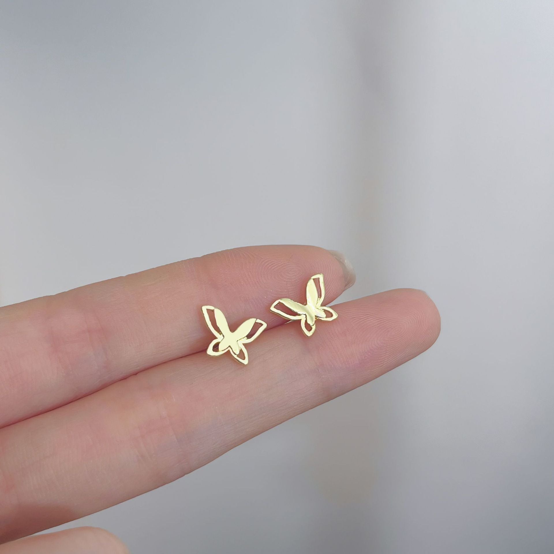 Gold butterfly earrings, designed for subtle sophistication, ideal for femboy fashion and casual styles.