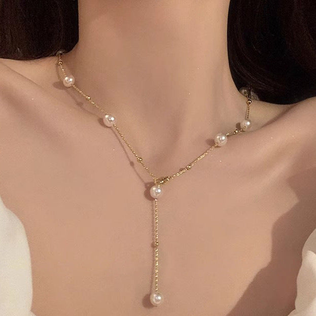 Gold and pearl drop necklace styled for minimalist and sophisticated femboy fashion aesthetics. Close up, front angle.