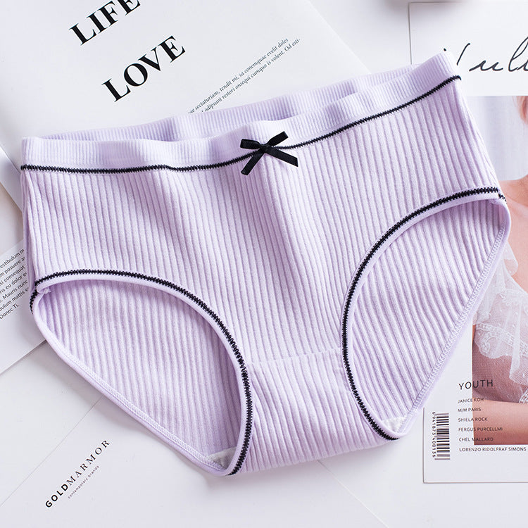 overhead shot of a lavender ribbed brief with scalloped lace trim and a neat black bow on a white background, ideal for flat-lay femboy outfit inspiration.