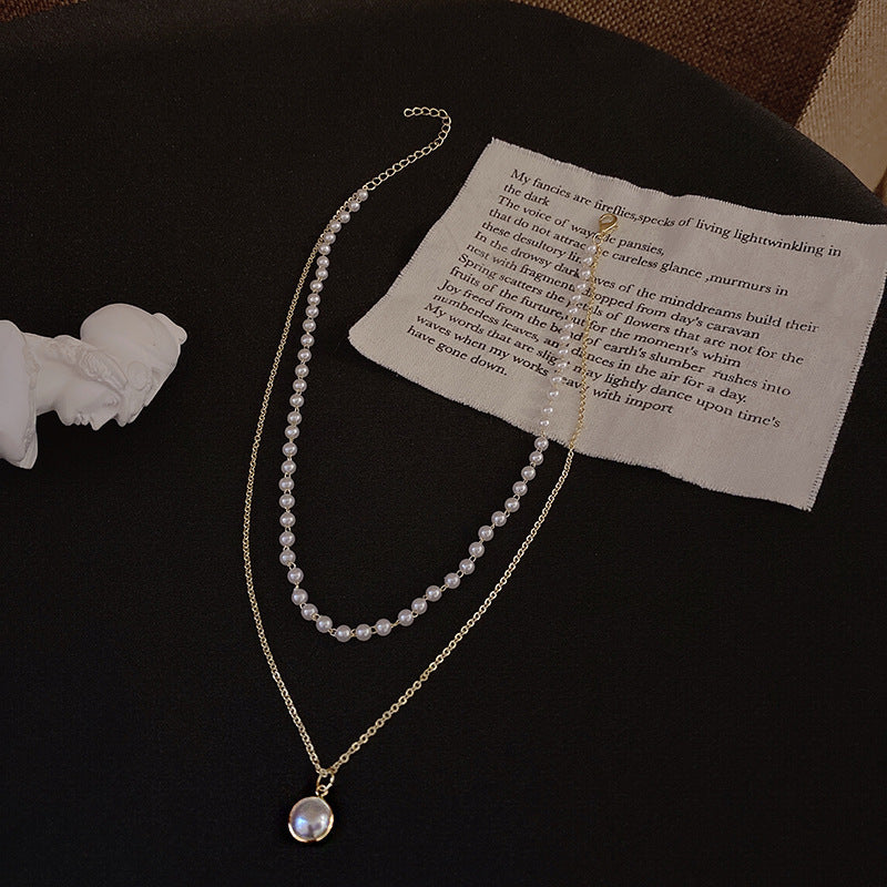 A flat-lay display of a double-layered pearl necklace with a gold pendant, perfect for chic femboy clothing ensembles.