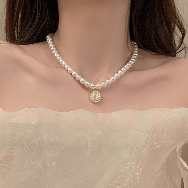 Elegant pearl choker with a vintage-inspired pendant styled against an off-shoulder dress for femboy outfits.