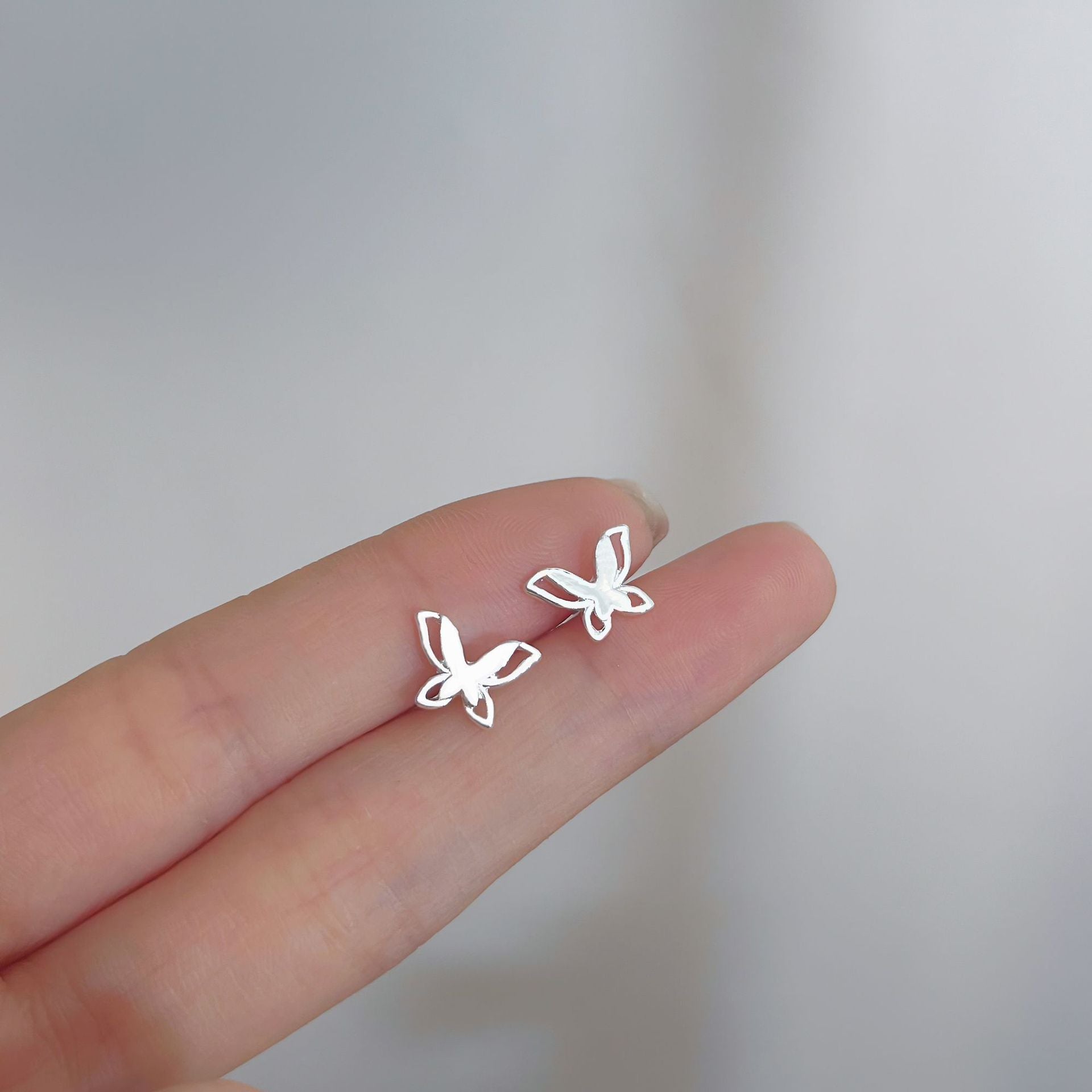 Silver butterfly earrings for a minimalist and elegant touch, perfect for femboy outfits and gender-neutral fashion.
