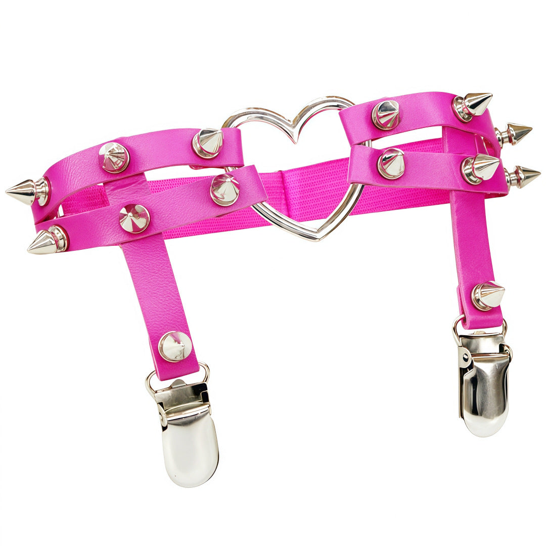 Angled studio product image of the hot pink Studded Heart Femboy Thigh Garter photographed from a slight three-quarter angle, showcasing vibrant pink faux leather, silver spike studs, heart-shaped metal centerpiece, and adjustable clips, a statement accessory for cute and sexy femboy outfits.