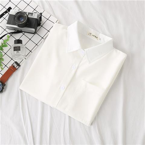 White short-sleeve button-up shirt folded neatly, clean minimalist femboy clothing essential photographed flat lay on white fabric background