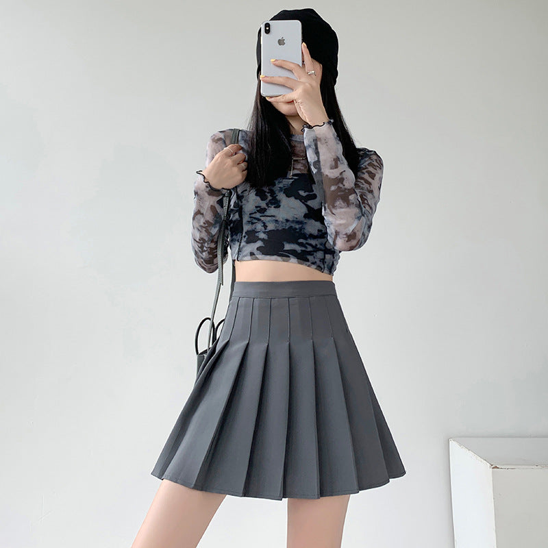 Full-body shot of a model wearing a gray high-waist pleated skirt and cropped long-sleeve top. The mirror selfie highlights the skirt’s pleated design and trendy fit, making it a great choice for femboy outfits. This chic skirt fits seamlessly into any femboy fashion wardrobe and represents an excellent addition to femboy clothing collections.