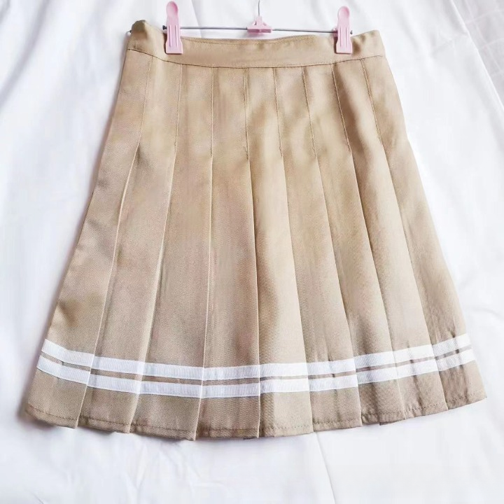 A close-up of a beige pleated skirt with white stripe accents, hung on a soft white background. The image showcases the design and structure of the skirt, ideal for femboy clothing enthusiasts looking for a versatile addition to their femboy outfits or femboy fashion collections.
