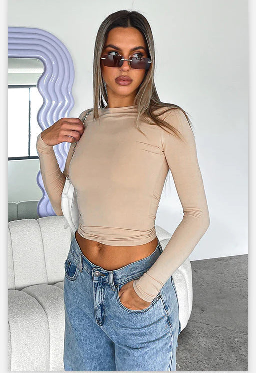 Model in a beige slim-fit long sleeve top, styled with high-waisted jeans, posing in a chic modern interior, ideal for femboy clothing enthusiasts.