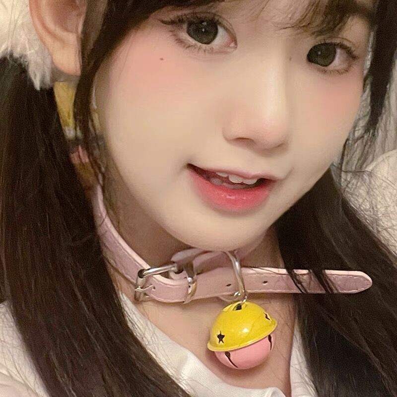 Pink bell collar femboy choker worn on model smiling, close-up portrait shot highlighting cute femboy outfit and pastel femboy fashion style