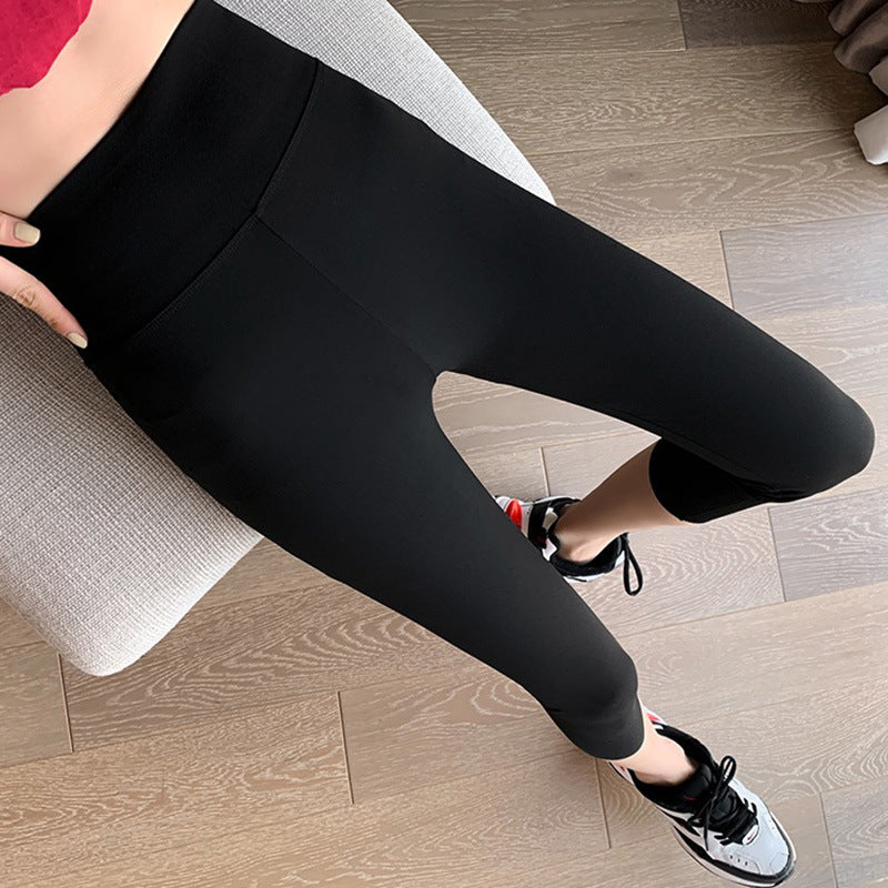 Close-up shot of black High Waist Yoga Leggings in capris length, paired with a cropped red top and sneakers. Captured indoors on a wooden floor, showcasing modern femboy outfits and activewear.