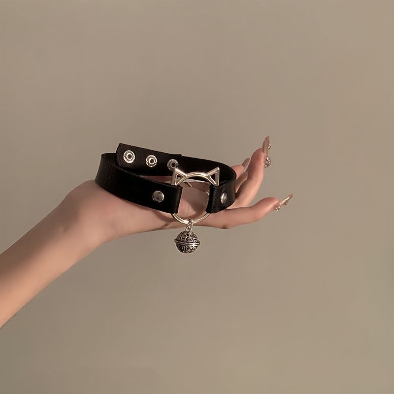 Close-up of a black cat-themed femboy choker with silver bell detail, held against a plain background, showcasing unique femboy accessory.