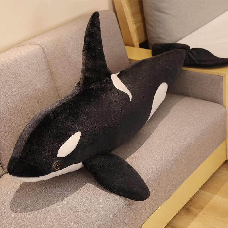 BLÅVINGAD orca plush resting on a sofa, displaying its full length, soft texture, and oversized body pillow form suitable for cuddling or room decor.