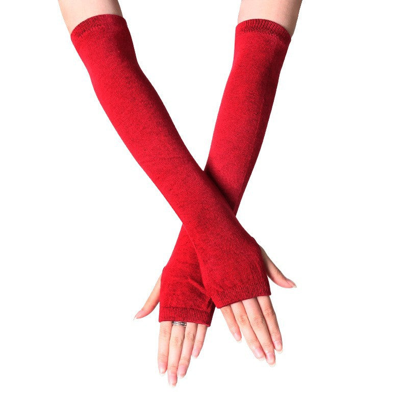 Close-up of hands wearing burgundy fingerless knit arm warmers, offering a vibrant look for femboy outfits. Perfect for adding a pop of colour to femboy clothing and winter fashion.