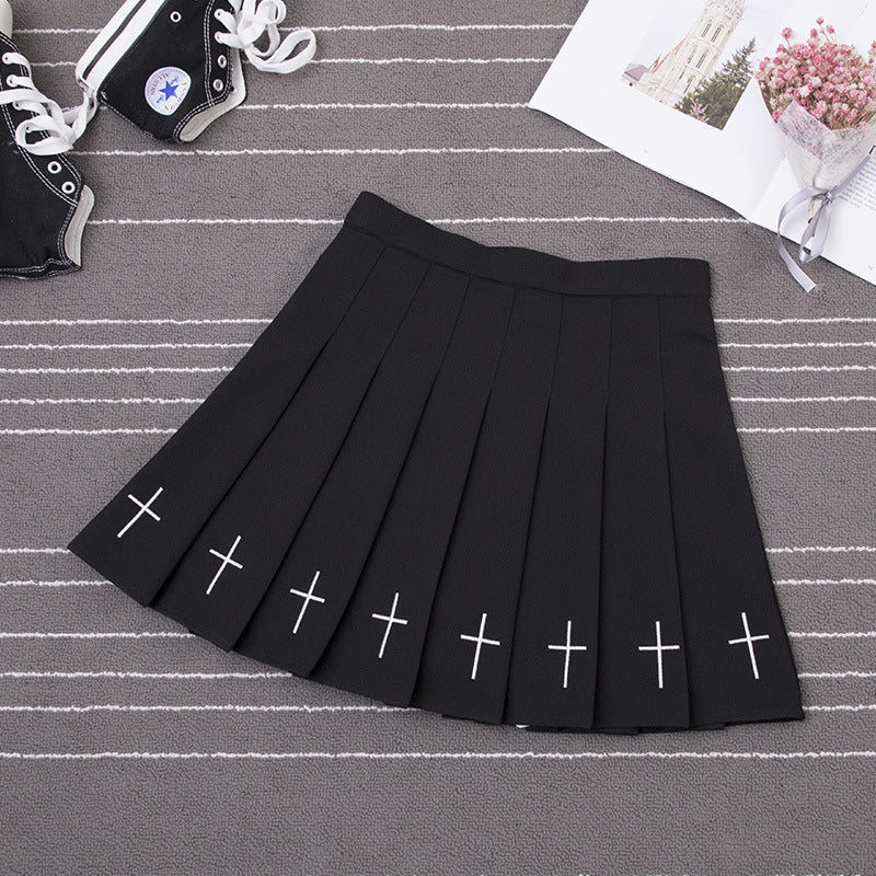 Close-up of a black Gothic Cross Pleated Skirt with distinctive white cross designs on the hem, showcasing modern femboy style.