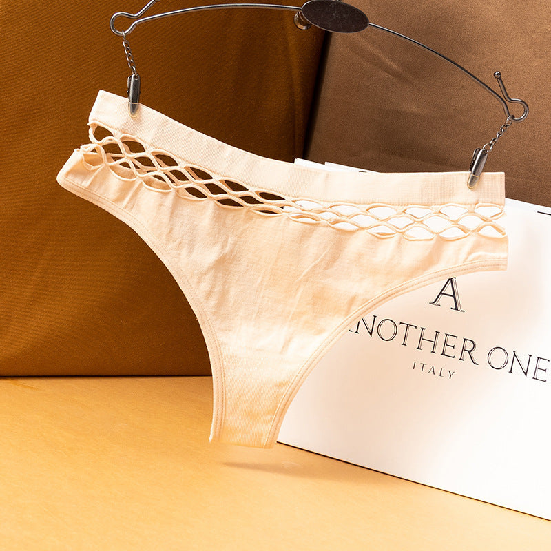 Cream fishnet femboy thong on metal hanger, front view showcasing woven cut-out waistband, warm studio backdrop