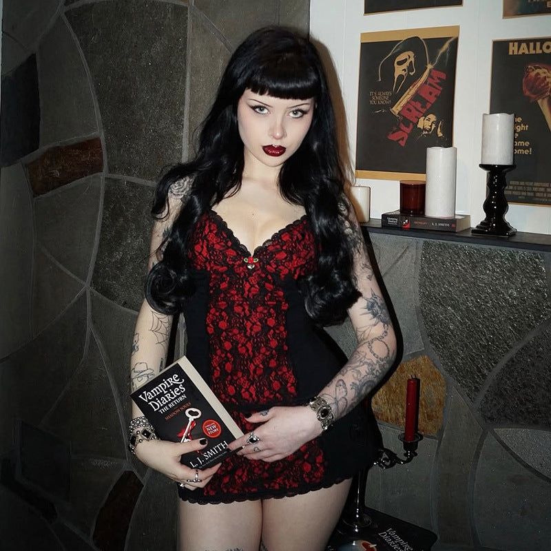 low-angle medium shot of a model cradling a horror paperback at waist level, highlighting the red lace front panel and slim fit of the cami against a moody grey backdrop, ideal for femboy outfits.