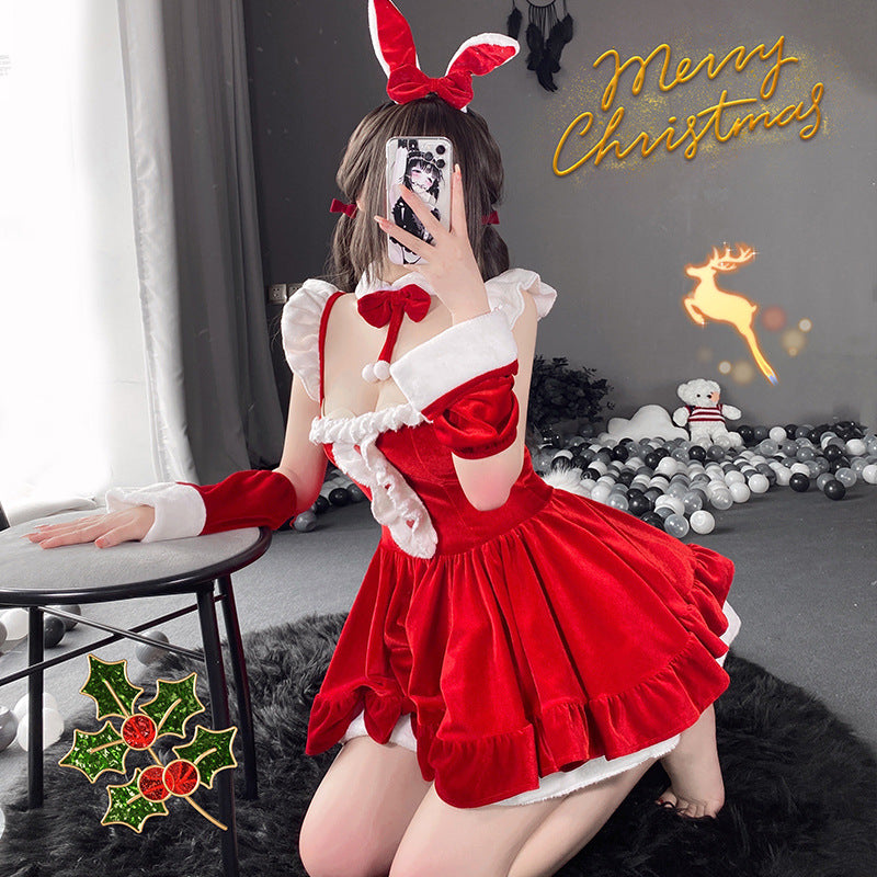 Medium shot of the Christmas Femboy Kit, featuring a layered red velvet dress with fur trim and holiday accessories, creating a playful, festive atmosphere for femboy fashion. Background shows Christmas decor, enhancing the holiday vibe.