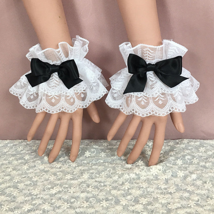 A close-up view of lace bracelets featuring sleek black bows on white lace, adding a touch of contrast and charm to the overall design. Displayed on mannequin hands, these accessories are ideal for complementing femboy clothes with their soft, romantic style.