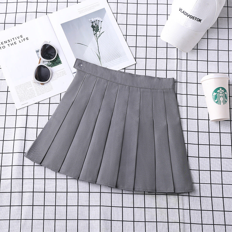 Modern femboy style featuring a grey high-waist pleated mini skirt laid flat with stylish accessories, perfect for femboy fashion enthusiasts.