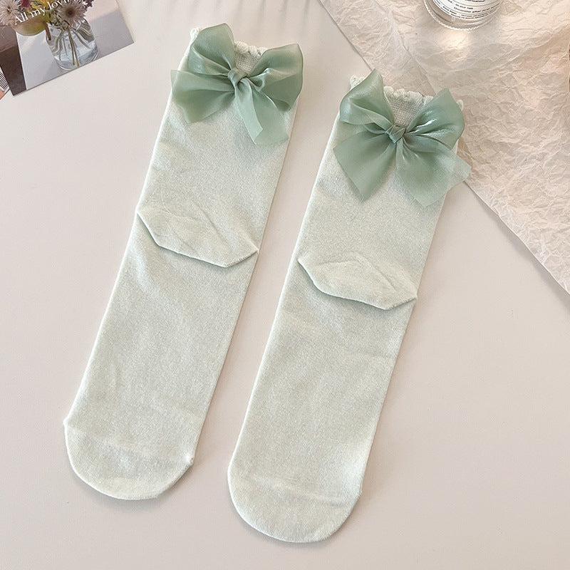 Top view of two Lolita Princess Socks in pastel green with lace trim and a bow at the heel, displayed on a white background.