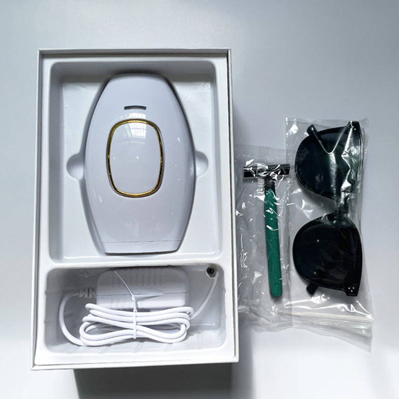 White femboy IPL hair removal device shown inside packaging with USB charger, razor, and protective eyewear, highlighting the full kit contents in a minimal flat-lay composition