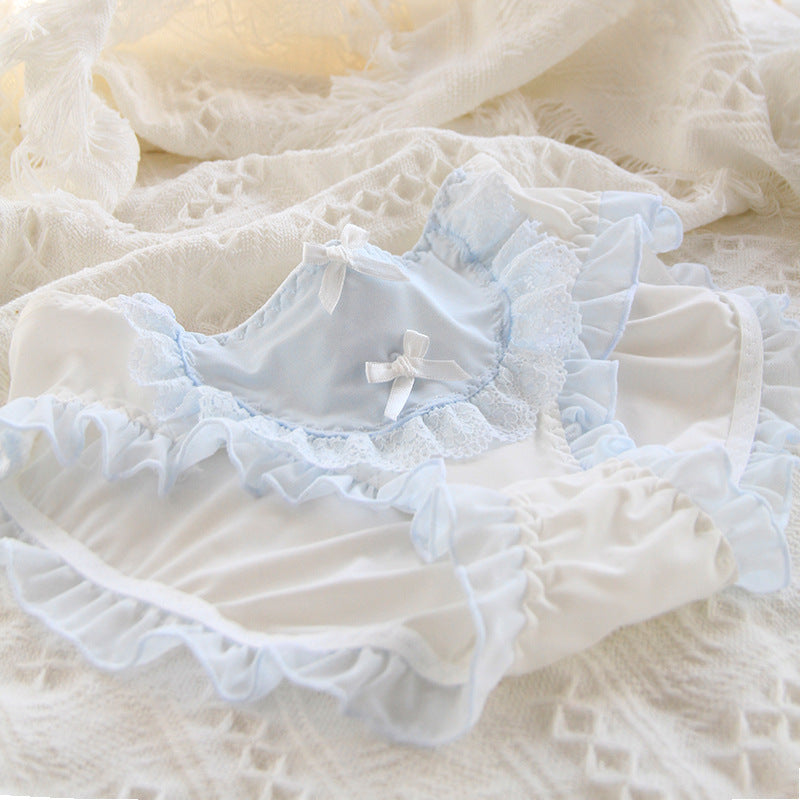 Soft-focus image of baby blue Lolita maid panties with lace and ribbon accents displayed on a soft white backdrop. The ruffled lace enhances the playful yet sophisticated style suitable for femboy outfits.