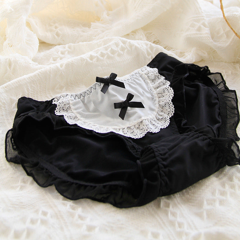 Close-up view of black and white Lolita maid panties with lace trim and bow details on a textured white background. The panties feature delicate lace edges, adding a touch of elegance and femininity to the design, ideal for femboy fashion.