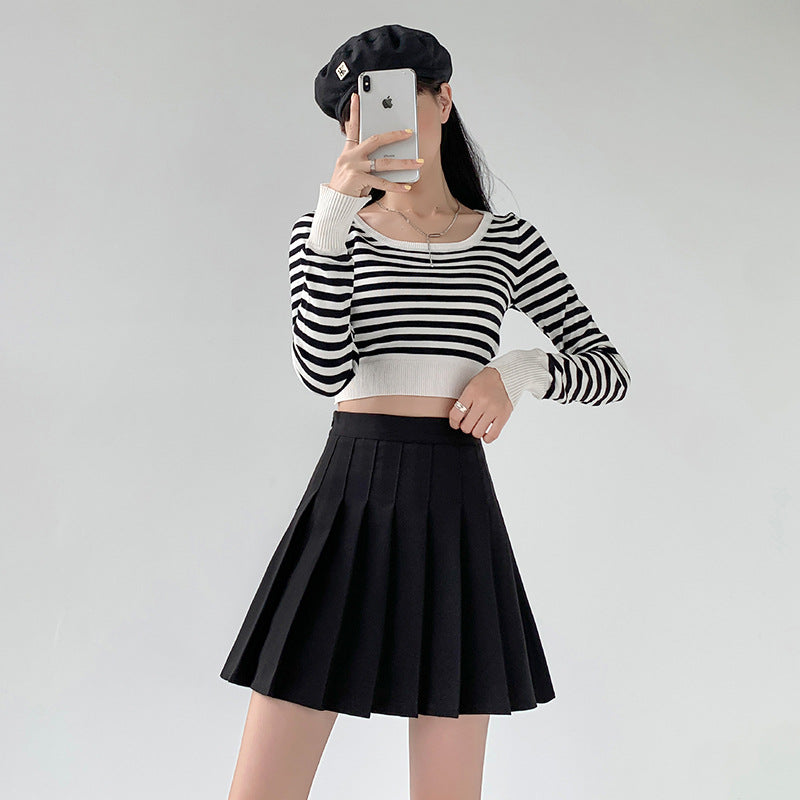 Full-body shot of a model wearing a black high-waist pleated skirt with a striped crop top, captured in a mirror selfie. The pleated skirt flows elegantly, representing casual yet chic femboy clothing. The combination makes for trendy femboy outfits that align with modern femboyhighlighting the flowy pleats of the skirt and the chic, casual look. This skirt is a key piece in femboy fashion, perfect for femboy outfits and femboy clothing collections. Keywords: femboy clothing, femboy outfits, femboy fashion.