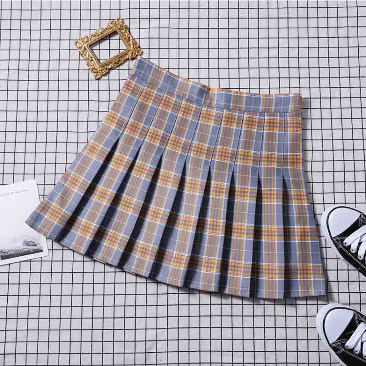 Grey plaid mini skirt laid flat over a grid backdrop, showcasing the intricate pleat details, perfect for femboy outfits.