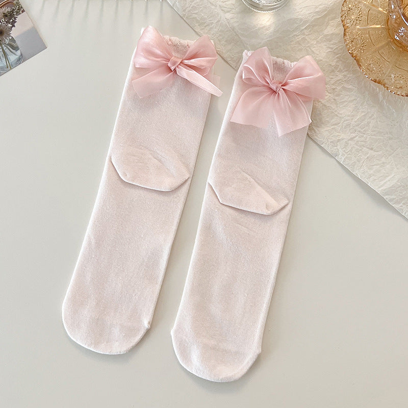 Top view of two Lolita Princess Socks in soft pink with lace detailing and a bow at the heel, laid on a white surface.