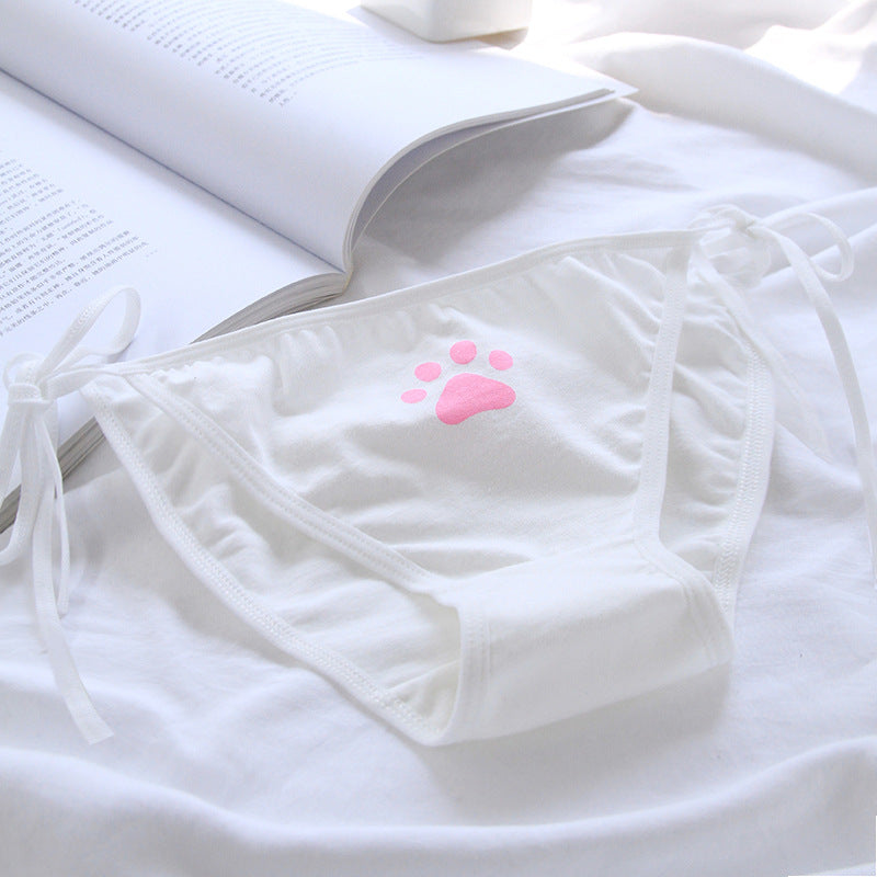 Close-up of white Paw Panties laid on a white background, featuring a cute pink paw print design. These femboy panties offer a playful touch to femboy outfits and femboy fashion.