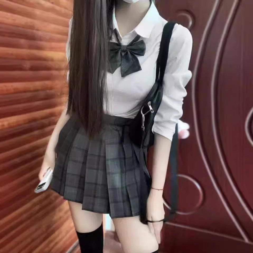 Full view of the Femboy Schoolgirl Kit featuring a white long sleeve shirt, plaid bow, and pleated skirt, paired with a black backpack for a trendy femboy fashion look.