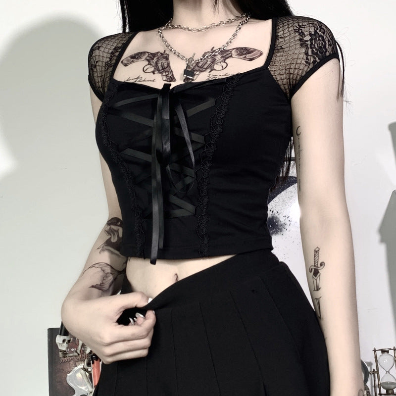 low-angle medium shot of a model adjusting a pleated skirt at the waist while wearing a lacey crop top with ribbon lacing, set before white cabinets, promoting femboy clothes shop.