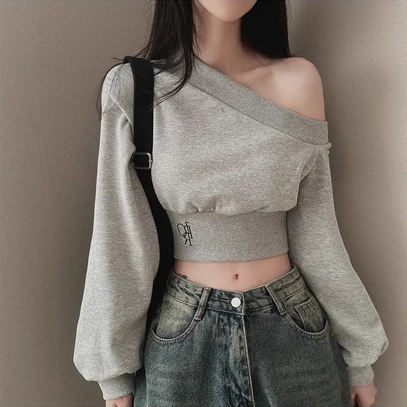 Front view portrait of model wearing grey half-shoulder cropped sweater with relaxed sleeves and asymmetrical neckline – casual femboy fashion, everyday femboy outfit