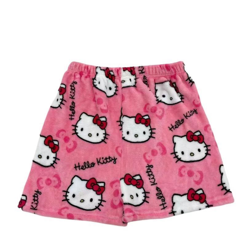 Flat lay close-up of pink plush Hello Kitty print shorts featuring oversized Hello Kitty faces, “Hello Kitty” text, and red bows; elastic waistband; white background product image for cozy femboy outfits.