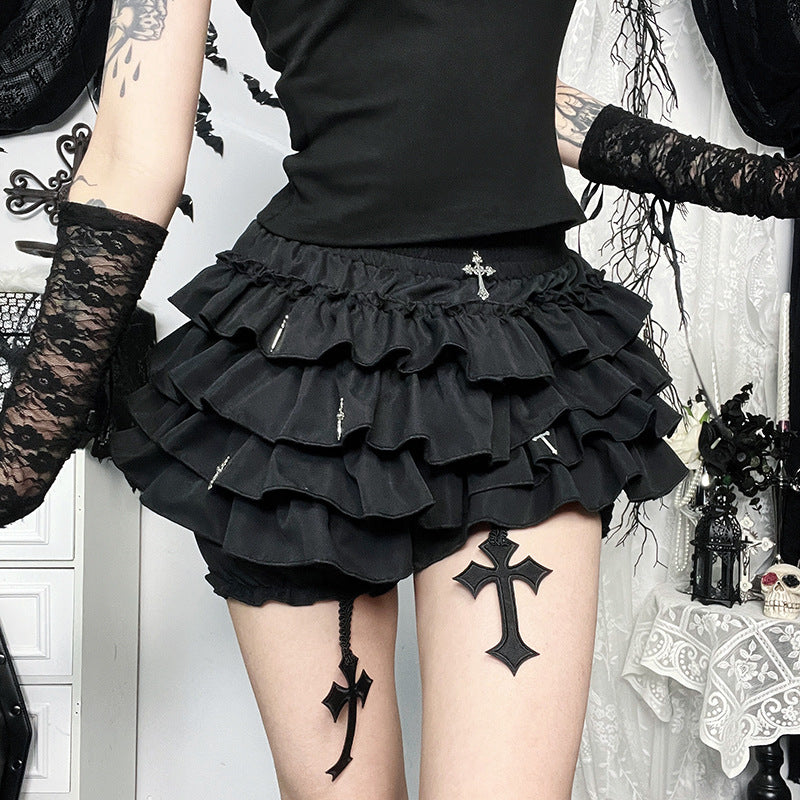 Side angle close-up of layered gothic black mini skirt with cross accents, lace sleeves, and alternative femboy outfit styling