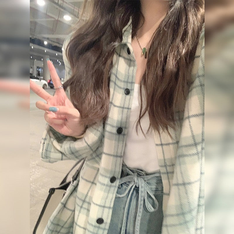 Close-up shot of a person wearing a light blue plaid button-up shirt layered over a white top, creating a stylish contrast. The shot is framed with a slight downward angle, capturing the trendy femboy clothing vibe. The soft plaid fabric and casual fit reflect effortless style.