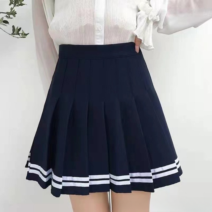 A navy pleated skirt with white stripes near the bottom, paired with a white blouse. The image is a mid-shot from waist to thigh, against a plain white background. The outfit highlights a clean and chic look in femboy fashion.