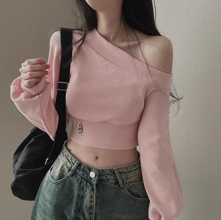 Front view portrait of model wearing pastel pink off-shoulder femboy crop top with soft knit texture and long sleeves – cute femboy outfit, feminine femboy fashion look