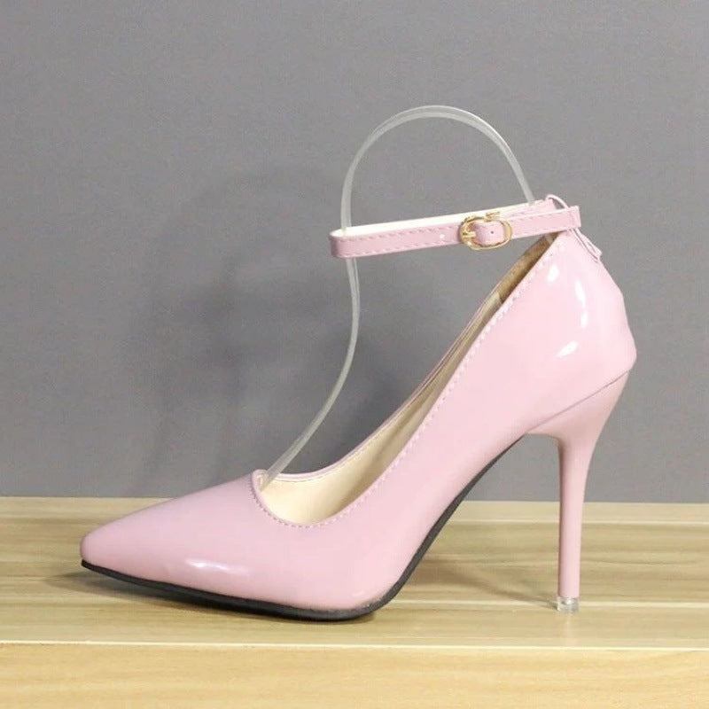 Angled view of chic pink leather heels with a 10 cm heel, highlighted by a polished finish and an ankle strap, placed on a wooden texture. Great for evening wear and femboy styles.