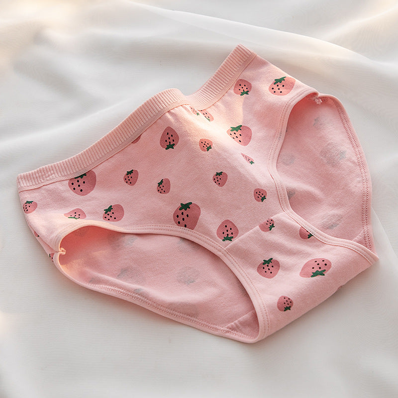 Close-up shot of a pink pair of strawberry print panties laid flat on a white surface. The soft cotton material and breathable design emphasize comfort and style in femboy clothing and femboy outfits. Background features soft natural light, adding a delicate touch to the display.