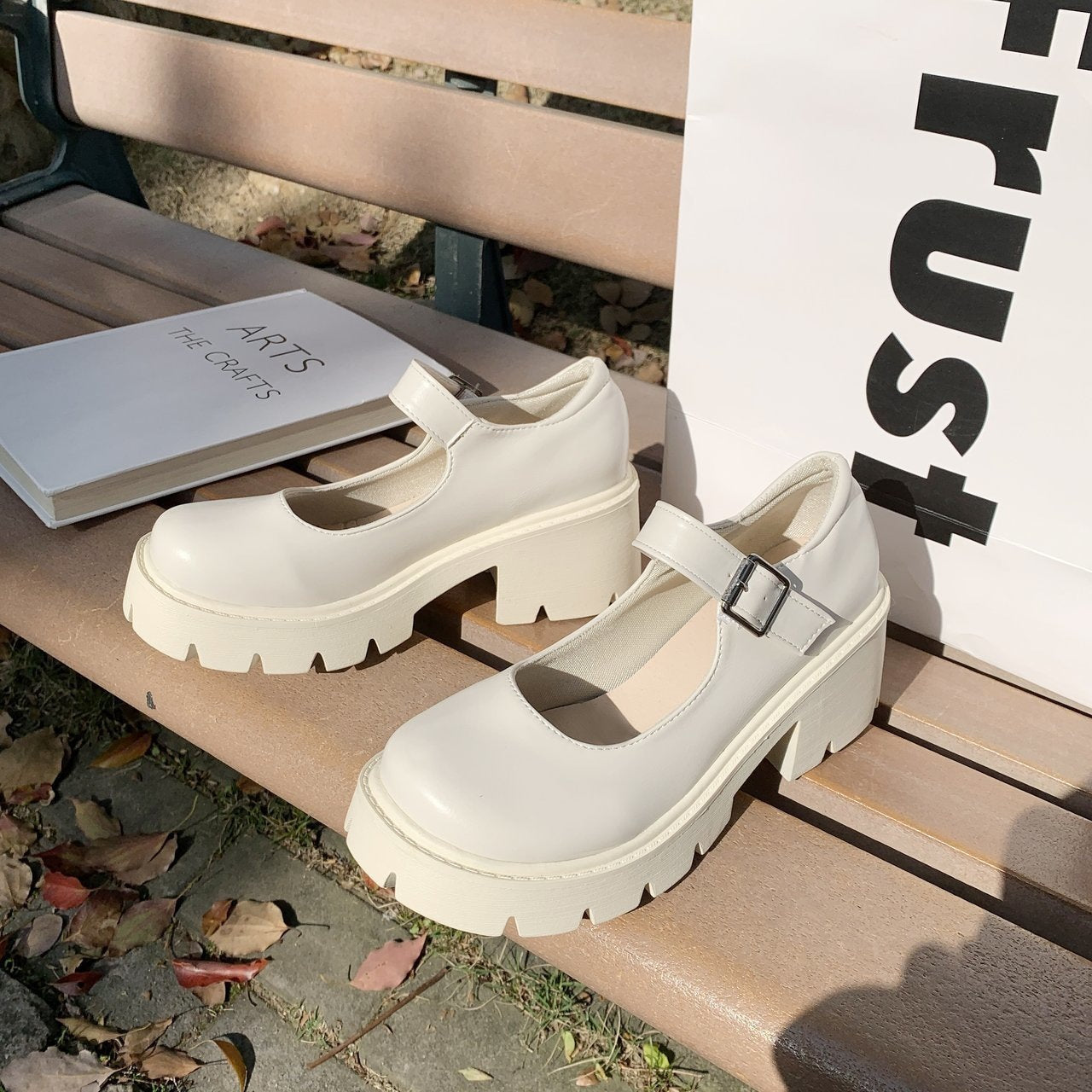 White school pumps with chunky heels displayed on a park bench under natural sunlight. Ideal for adding a classic touch to femboy style and outfits.